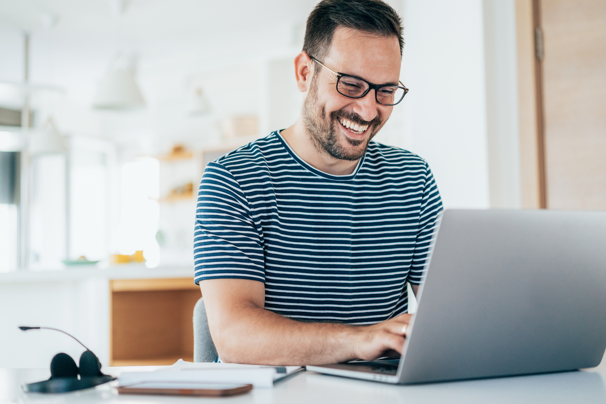 Handsome businessman working at home using laptop smiling